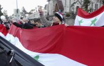 A pro-Assad demonstrator gestures as he holds the Syrian national flag in front of the venue where the Syria peace conference is held, in Montreux January 22, 2014. Syria's government and opposition, meeting face to face for the first time at a U.N. peace conference, angrily spelled out their hostility on Wednesday as world powers also restated contrasting views on the future of President Bashar al-Assad. (REUTERS/ Kinda Makieh)