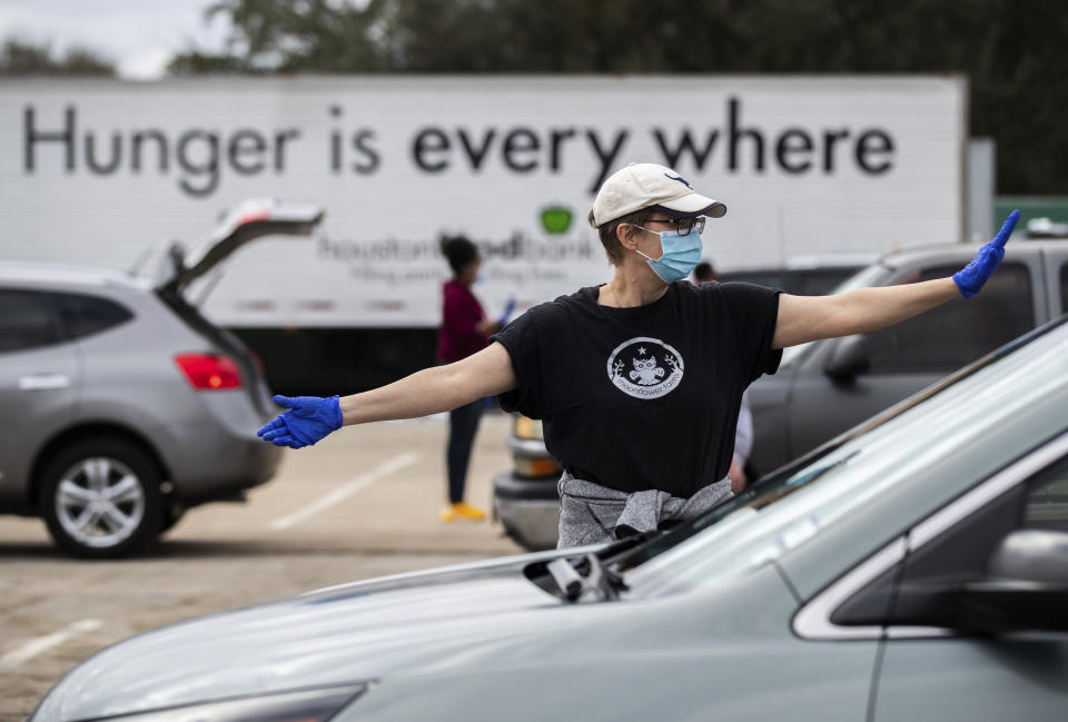 Houston Food Bank volunteer Cecilie Tindlund directs traffic during a food distribution event at NRG Park, Sunday, Feb. 21, 2021, in Houston. (Marie D. De Jesús/Houston Chronicle via AP)