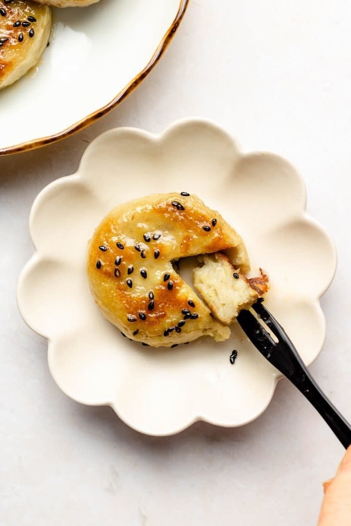 A fresh serving of sweet potato yaki mochi topped with black sesame seeds, with a fork pulling out a piece to show its dense core.