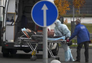 Medical workers carry a patient suspected of having coronavirus on a stretcher at a hospital in Kommunarka, outside Moscow, Russia, Tuesday, Oct. 12, 2021. Russia hit another record of daily coronavirus deaths Tuesday as the country struggled with a rapid surge of infections and lagging vaccination rates, but authorities have been adamant that there would be no new national lockdown. (AP Photo/Alexander Zemlianichenko)