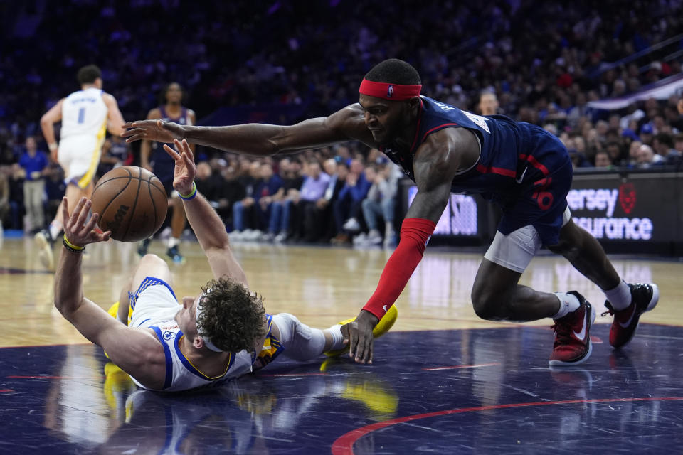 Philadelphia 76ers' Paul Reed, right, and Golden State Warriors' Brandin Podziemski chase a loose ball during the first half of an NBA basketball game, Wednesday, Feb. 7, 2024, in Philadelphia. (AP Photo/Matt Slocum)