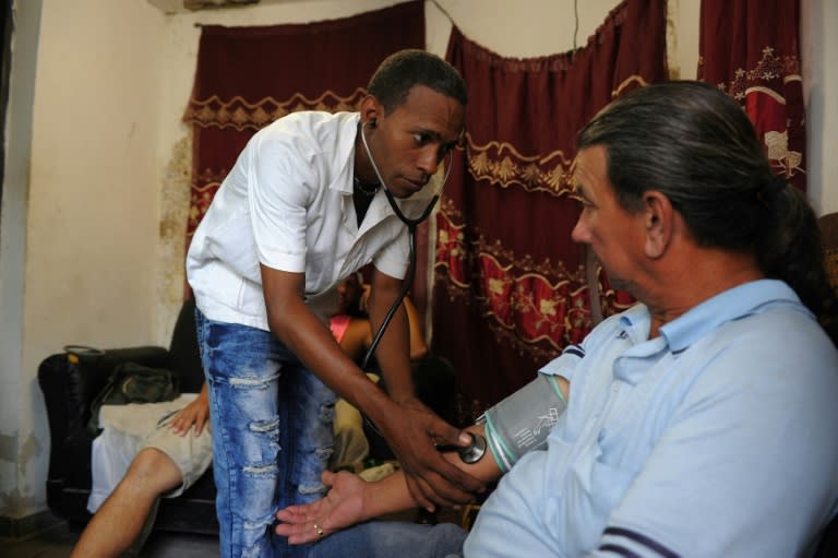 Jose Antonio Torres, a nurse who now works as a 'bicitaxi' or bicycle taxi driver, takes a friend's blood pressure in Havana