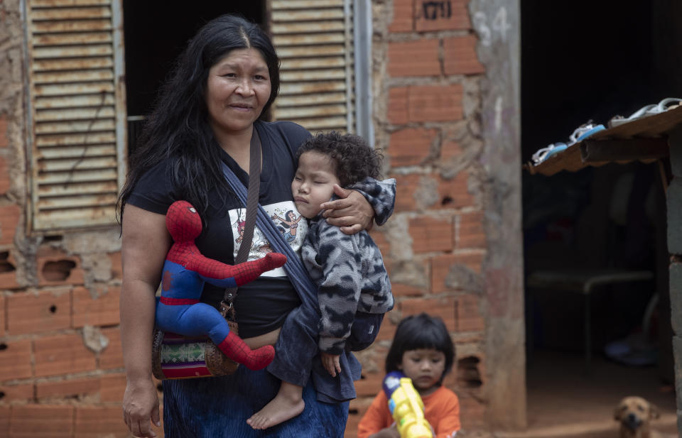 A Guarani Mbya woman with her son and his Spiderman doll walks outside, on her indigenous community's property in Sao Paulo, Brazil, Friday, Jan. 31, 2020. Members of the tribe, living in the smallest demarcated indigenous land of Brazil, were surprised by workers with chainsaws who were making way for a five-building apartment complex in a nearby forested area. They say they weren’t consulted, as the law states, but the company has permits to build. The tension between a builder with projects in nine Brazilian states and a 40-family indigenous community is a microcosm of what’s playing out elsewhere in the country. (AP Photo/Andre Penner)