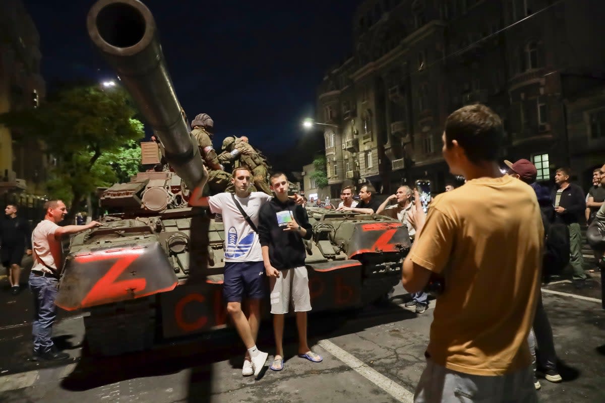 Wagner Group servicemen sit on top of a tank as local civilians pose for a photo in Rostov-on-Don (AP)