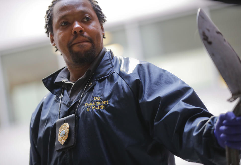 Pest Control Officer Andre Pitman, from the D.C. Department of Health's Rodent Control Division, with his badge and shovel, two tools he uses on the job, during an inspection of an alley in downtown Washington, Wednesday, Oct. 17, 2019. The nation’s capital is facing a spiraling rat infestation, fueled by mild winters and a human population boom. Washington’s government is struggling to keep pace(AP Photo/Pablo Martinez Monsivais)