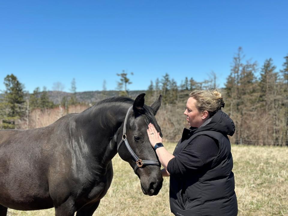 Lindsay Steele stands with one of her mares on her property in Scots Bay. She's worried a proposed campground next door would be detrimental to her horse-breeding and farming businesses.