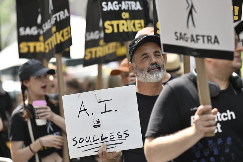 Picketers carry signs outside NBC in Rockefeller Center on Monday, July 17, 2023, in New York.