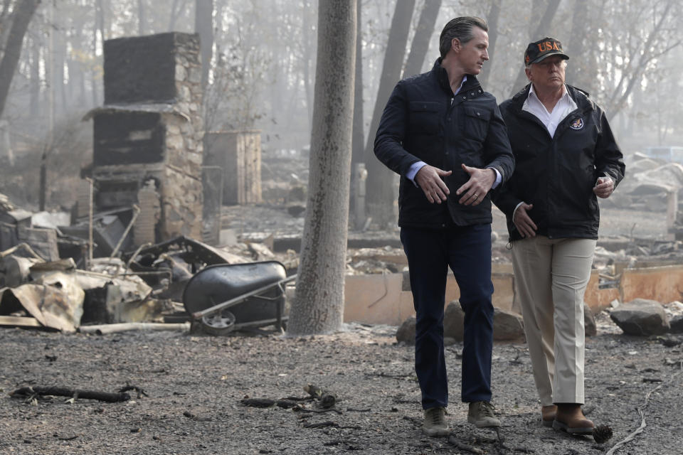 FILE - In this Nov. 17, 2018, file photo, President Donald Trump talks with then California Gov.-elect Gavin Newsom during a visit to a neighborhood destroyed by the wildfires in Paradise, Calif. Gov. Newsom is wrapping up a first year highlighted by the bankruptcy of the country's largest utility, an escalating homelessness crisis and an intensifying feud with the Trump administration, along with record-low unemployment and a booming state economy producing a multi-billion-dollar surplus. (AP Photo/Evan Vucci, File)