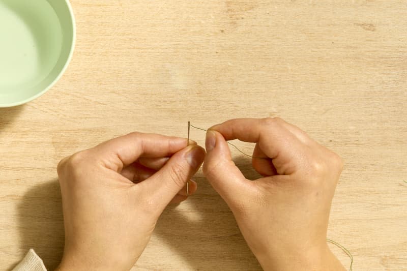 Overhead shot of a hand threading a needle.