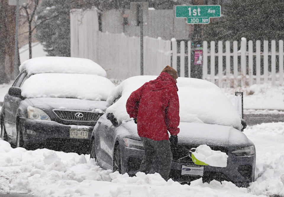 A motorist struggles to clear snow from in front of a vehicle parked along Washington Street as a late winter storm regained force late Thursday, March 14, 2024, in Denver. Forecasters predict that the storm, which has already dropped a foot or more of snow, will persist until early Friday, snarling traffic along Colorado's Front Range communities. (AP Photo/David Zalubowski)