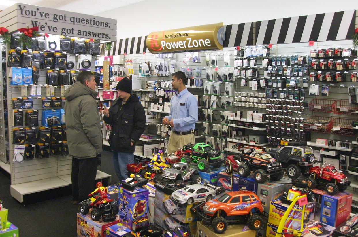 Sales associate Raheel Hameed (R) assists customers at a Radio Shack store January 3, 2002 in Skokie, IL.