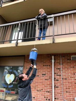 A Monroe County Opportunity Program staff member hoists food up to a senior resident at the Mable Kehres Apartment Complex in Monroe Township in April. The resident was concerned about possible exposure to COVID-19, so MCOP rigged a pulley system to deliver food while maintaining social distancing.
