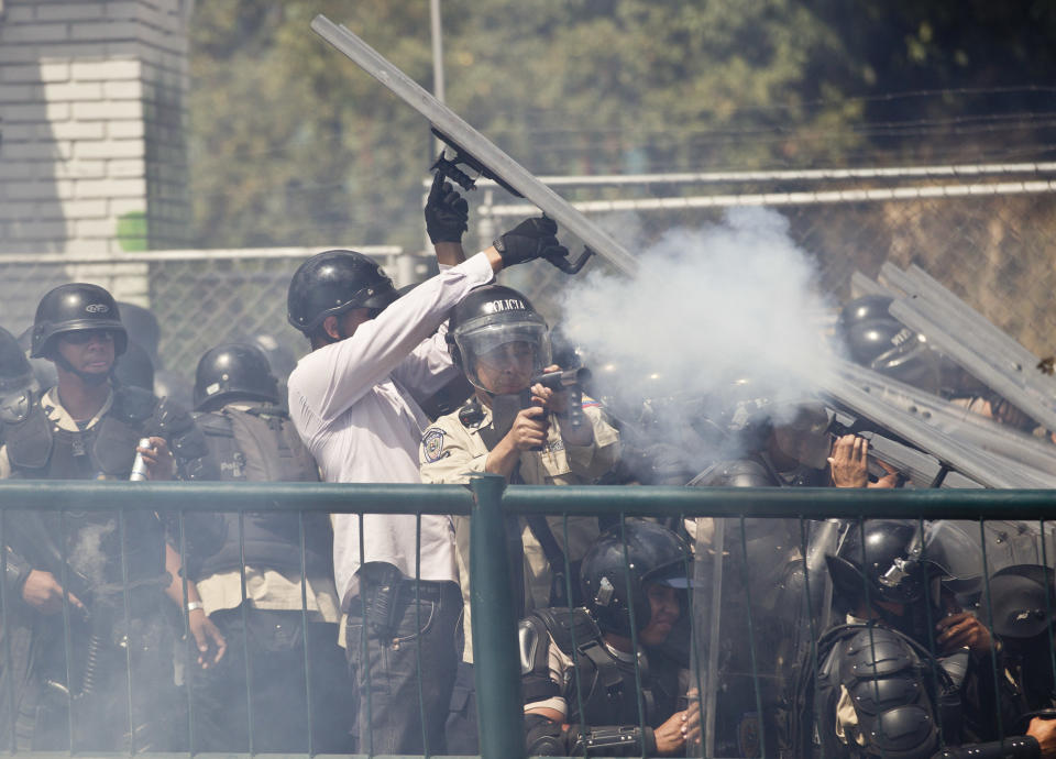 A member of the Bolivarian National Police fires tear gas at protesters in Caracas, Venezuela, Thursday, March 20, 2014. Thursday dawned with two more opposition politicians, San Cristobal Mayor Daniel Ceballos and San Diego Mayor Enzo Scarano, behind bars. Police used tear gas and water cannons to disperse a student-called protest of several thousand people in Caracas, some of those demonstrating against the arrests of the mayors. (AP Photo/Esteban Felix)