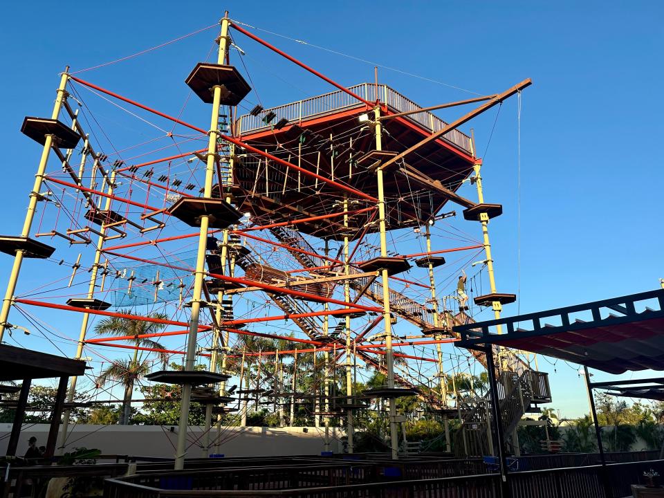 ropes suspended between red and yellow poles in the air