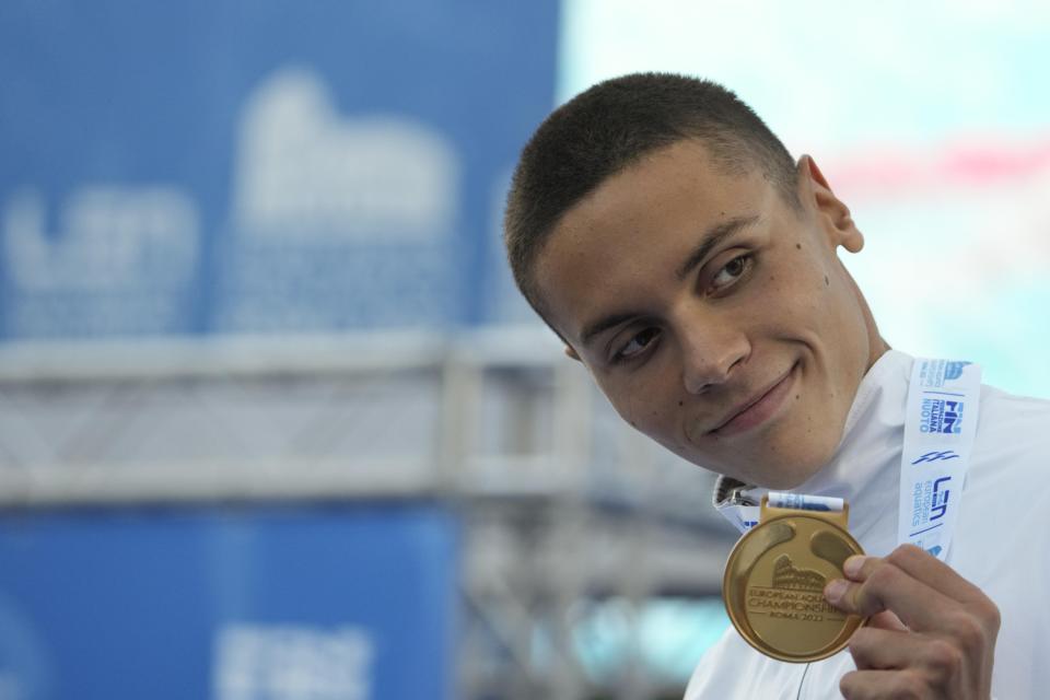 First placed Romania's David Popovici celebrates on the podium of the men's 100m freestyle final at the European swimming championships, in Rome, Saturday, Aug. 13, 2022. (AP Photo/Andrew Medichini)