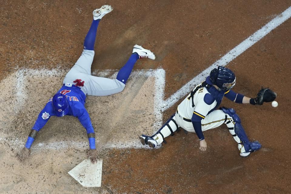Chicago Cubs' Nelson Velazquez slides safely past Milwaukee Brewers catcher Victor Caratini during the sixth inning of a baseball game Tuesday, July 5, 2022, in Milwaukee. Velazquez scored on a hit by Rafael Ortega. (AP Photo/Morry Gash)