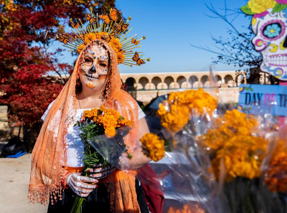 Laura Gonzalez, owner of Unforgettable Moments, holds marigolds, flowers used to decorate ofrendas (altars) as she is dressed as a Catrina for the Día de los Muertos celebration on Saturday, Oct. 29, 2022, at Forest Home Cemetery in Milwaukee, Wis.