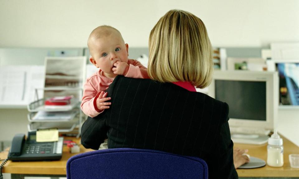 Woman at desk holding baby.