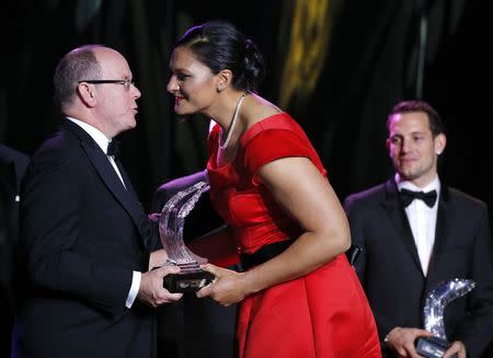 Shot putter Valerie Adams of New Zealand (C) receives her 2014 IAAF Athlete of the Year trophy from Prince Albert II of Monaco (L) as World-record pole vaulter Renaud Lavillenie (R) of France looks on during the IAAF Gala in Monte Carlo November 21, 2014. REUTERS/Eric Gaillard