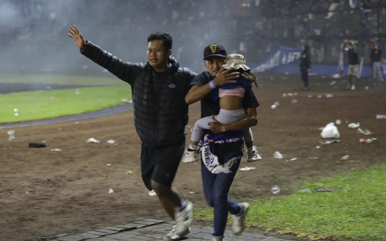 Indonesian football stampede - Fans evacuate a girl during clashes at Kanjuruhan Stadium - H PRABOWO/EPA-EFE/Shutterstock