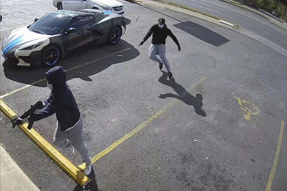 This video image provided by the Memphis Police Department, show two people with guns drawn after leaving their vehicle, a white Mercedes-Benz, who authorities say are involved in the shooting of 36-year-old rapper Young Dolph on Wednesday, Nov. 17, 2021. Police have scoured the city of Thursday as they searched for suspects. (Memphis Police Department via AP)