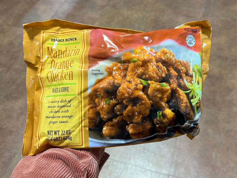 The writer holds a bag of Trader Joe's Mandarin orange chicken