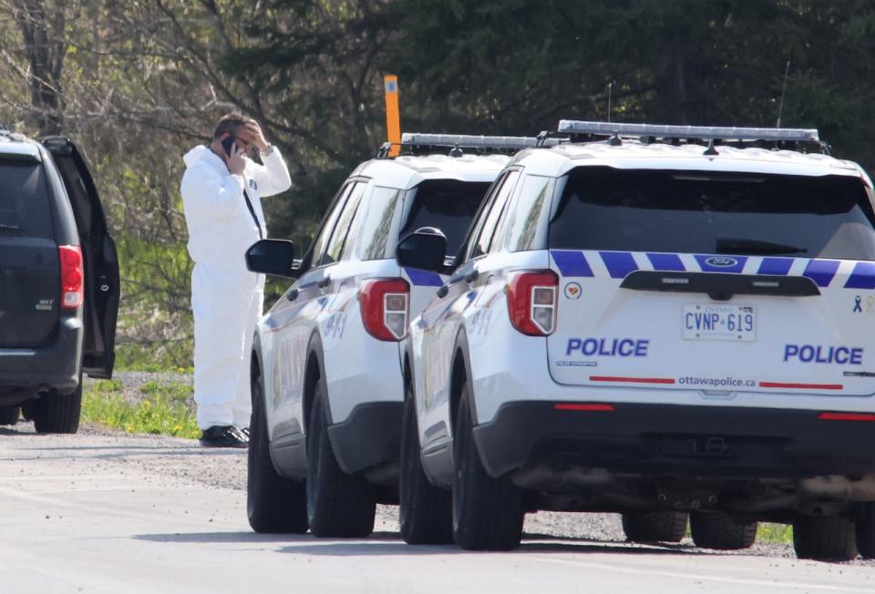 An investigator talks on a cellphone near the scene of a shooting, where one Ontario Provincial Police officer was killed and two others were injured, in the town of Bourget, Ont., on Thursday, May 11, 2023.