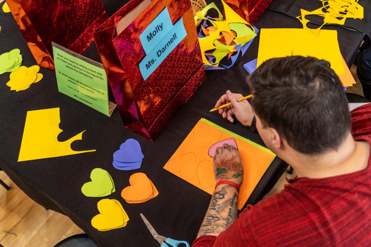 Counselor Kevin Smith traces outlines to cut heart-shaped pieces of paper at Willows Edge Counseling and Healing Arts in downtown Oxford on Thursday, Dec. 2, 2021, for people to write messages to families of the gunshot victims of a mass shooting two days earlier.