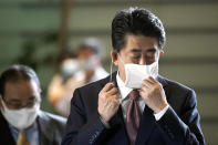 Japan's outgoing Prime Minister Shinzo Abe takes off his face mask as he arrives at the prime minister's office for a cabniet meeting Wednesday, Sept. 16, 2020, in Tokyo. Abe and his Cabinet resigned, clearing the way for his successor Yoshihide Suga to take over after parliamentary confirmation later in the day. (AP Photo/Eugene Hoshiko)