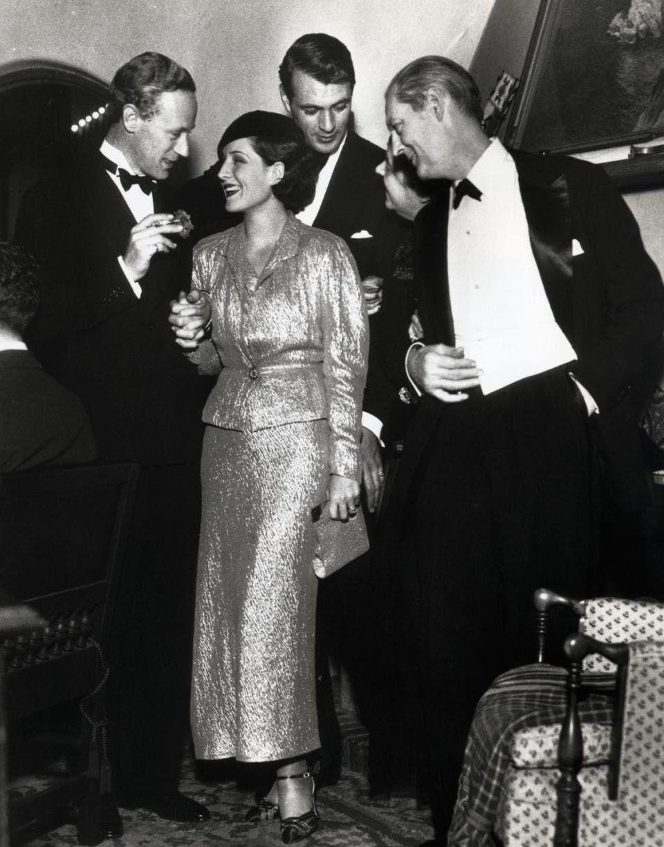 <p>Norma Shearer knows that you can't go wrong with a gilded gown at a holiday party. The actress dressed in a gold lamé coat dress while attending Gary Cooper's Christmas party.</p>