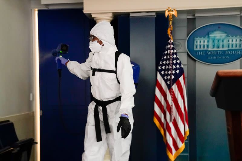 A member of the White House cleaning staff sprays the press briefing room the evening of U.S. President Donald Trump's return from Walter Reed Medical Center