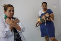 A physiotherapist gestures as Jaqueline (R), 25, holds her five-month-old daughter Laura during an evaluation session at the Casa da Esperanca Hospital (Hope House Hospital) in Santos, Sao Paulo state, Brazil April 20, 2016. REUTERS/Nacho Doce