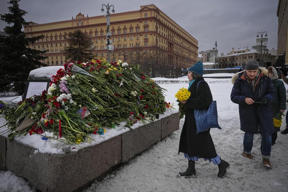 People lay flowers paying the last respect to Alexei Navalny at the monument, a large boulder from the Solovetsky islands, where the first camp of the Gulag political prison system was established, with the historical the Federal Security Service (FSB, Soviet KGB successor) building in the background, in Moscow, Russia, on Saturday morning, Feb. 17, 2024. Russian authorities say that Alexei Navalny, the fiercest foe of Russian President Vladimir Putin who crusaded against official corruption and staged massive anti-Kremlin protests, died in prison. He was 47. (AP Photo/Alexander Zemlianichenko)