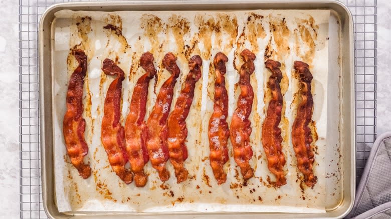 Cooked bacon strips on baking sheet