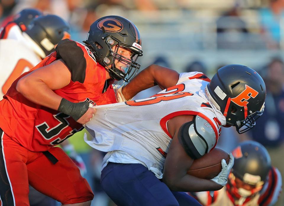 Green defensive lineman Michael Schaal, left, brings down Ellet running back Terrance Thomas Jr. for a loss, Aug. 19, 2022.