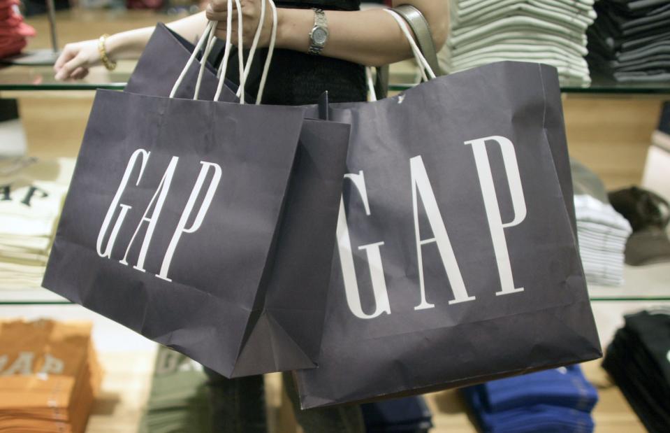 A arm holding three navy blue GAP paper bags