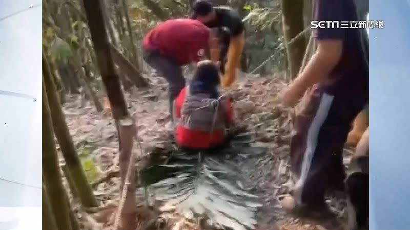 救難人員用大樹葉代替擔架護送婦人。