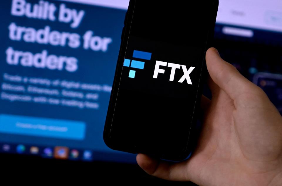 This illustration photo shows a smart phone screen displaying the logo of FTX, the crypto exchange platform, with a screen showing the FTX website in the background in Arlington, Virginia on February 10, 2022. - Sam Bankman-Fried donned a suit and tie this week, abandoning his preferred hoodie and dark T-shirt for a hearing before US Senators.  The lawmakers had summoned the 29-year-old multi-billionaire on Wednesday to discuss the regulation of digital assets in his capacity as co-founder and CEO of the cryptocurrency exchange platform FTX (Photo by OLIVIER DOULIERY / AFP) (Photo by OLIVIER DOULIERY/AFP via Getty Images)