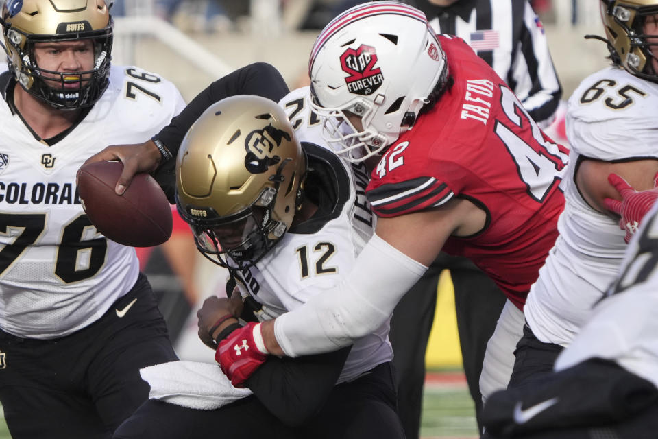 Colorado quarterback Brendon Lewis (12) breaks loose from a tackle by Utah defensive end Mika Tafua (42) in the first half of an NCAA college football game Friday, Nov. 26, 2021, in Salt Lake City. (AP Photo/George Frey)