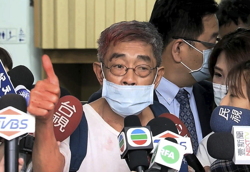In this image made from video, Lam Wing-kee, center, founder of Hong Kong’s Causeway Bay Book shop speaks to journalists in Taipei Tuesday, April 21, 2020. Lam was attacked by an unidentified man who threw red paint at him on Tuesday morning in Taipei. According to police, an unknown man in mask and dark clothes suddenly came to throw red paint at Lam while he was alone at a coffee shop. (EBC via AP)