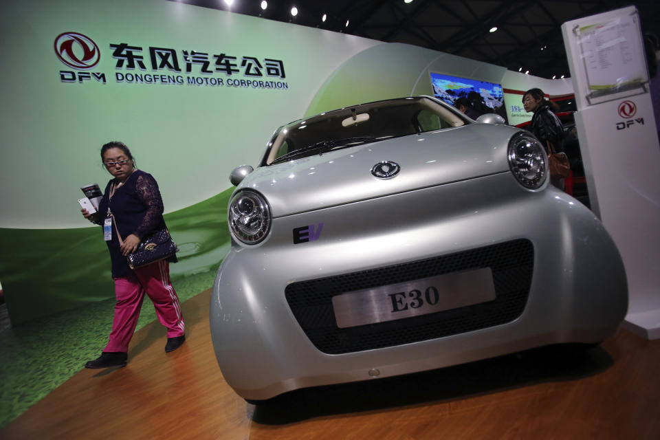 FILE - In this Nov. 5, 2013 file photo, a visitor looks at an E30 EV, a small electric vehicle of Chinese state-owned automobile manufacturer Dongfeng Motor Co., at China International Industry Fair in Shanghai, China. Chinese automaker Dongfeng said Wednesday, Feb. 19, 2014, it will invest 800 million euros ($1.1 billion) in France's Peugeot and expand cooperation in China's fast-growing market. (AP Photo/Eugene Hoshiko, File)