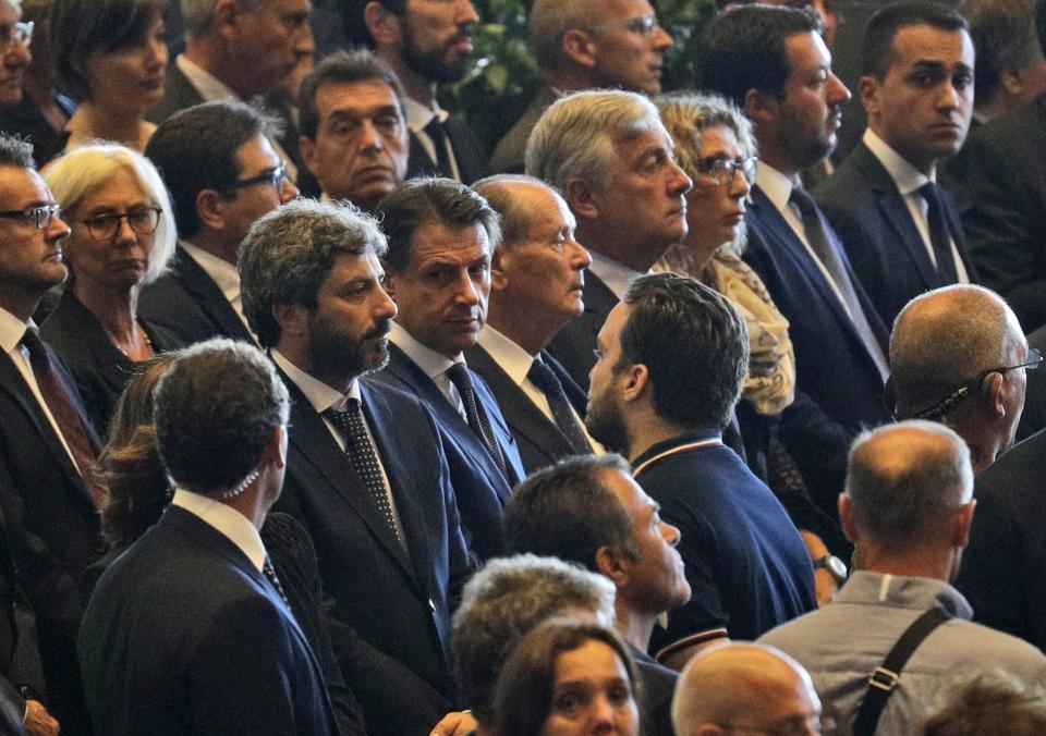 Italian Premier Giuseppe Conte, center, is flanked by Lower Chamber of Deputies president Roberto Fico, left, and Deputy Prime Minister of Italy and Minister of Economic Development, Labour and Social Policies Luigi Di Maio, right, Deputy Premier and Interior Minister Matteo Salvini, second from right, and President of the European Parliament Antonio Tajani, fourth from right, as they attend a funeral service for some of the victims of a collapsed highway bridge, in Genoa's exhibition center Fiera di Genova, Italy, Saturday, Aug. 18, 2018. Saturday has been declared a national day of mourning in Italy and includes a state funeral at the industrial port city's fair grounds for those who plunged to their deaths as the 45-meter (150-foot) tall Morandi Bridge gave way Tuesday. (AP Photo/Gregorio Borgia)