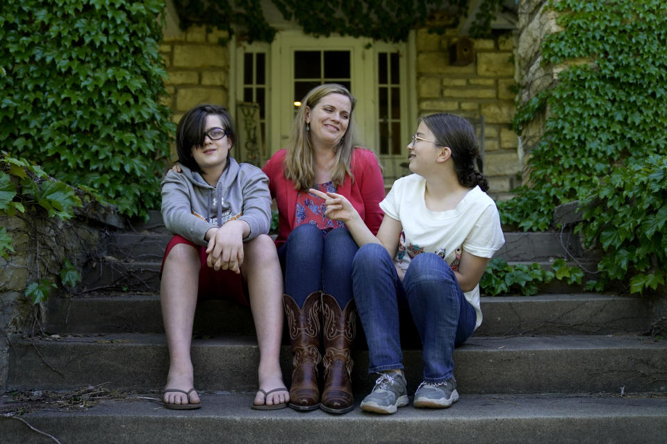 Heather Ousley sits with her older children Elliannah, 15, right, and Samuel, 13, in front of their home in Merriam, Kan, Tuesday, May 4, 2021. Ousley was thrilled when she heard the FDA was expected to authorize Pfizer's COVID-19 vaccine for youngsters ages 12 to 15 and was hoping to get her kids vaccinated as soon as she can. (AP Photo/Charlie Riedel)