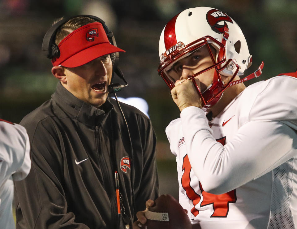 Western Kentucky coach Mike Sanford talks to quarterback Mike White (14) during an NCAA college football game against Marshall on Saturday, Nov. 11, 2017, in Huntington, W. Va. (Austin Anthony/Daily News via AP)