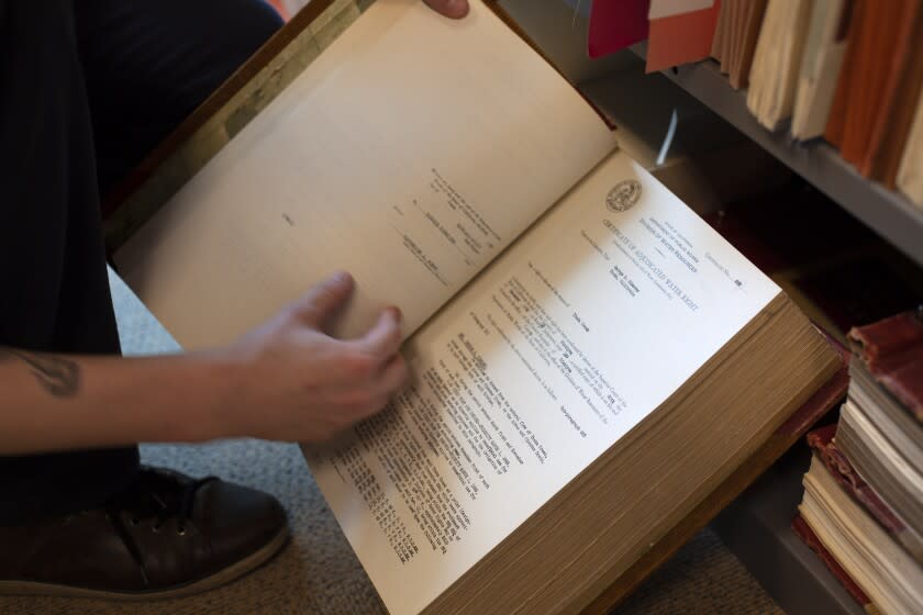 Matthew Jay, an analyst at the State Water Resources Control Board, holds a thick volume of adjudicated water rights certificates. After 13 years, he knows the room better than anyone else at the agency. (Ari Plachta / Los Angeles Times)