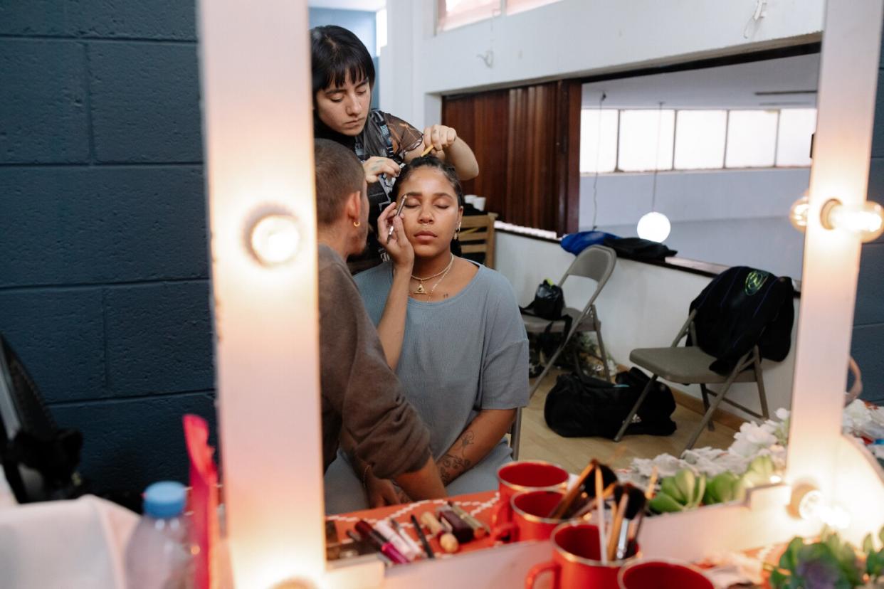 A woman gets attended to by makeup artists.