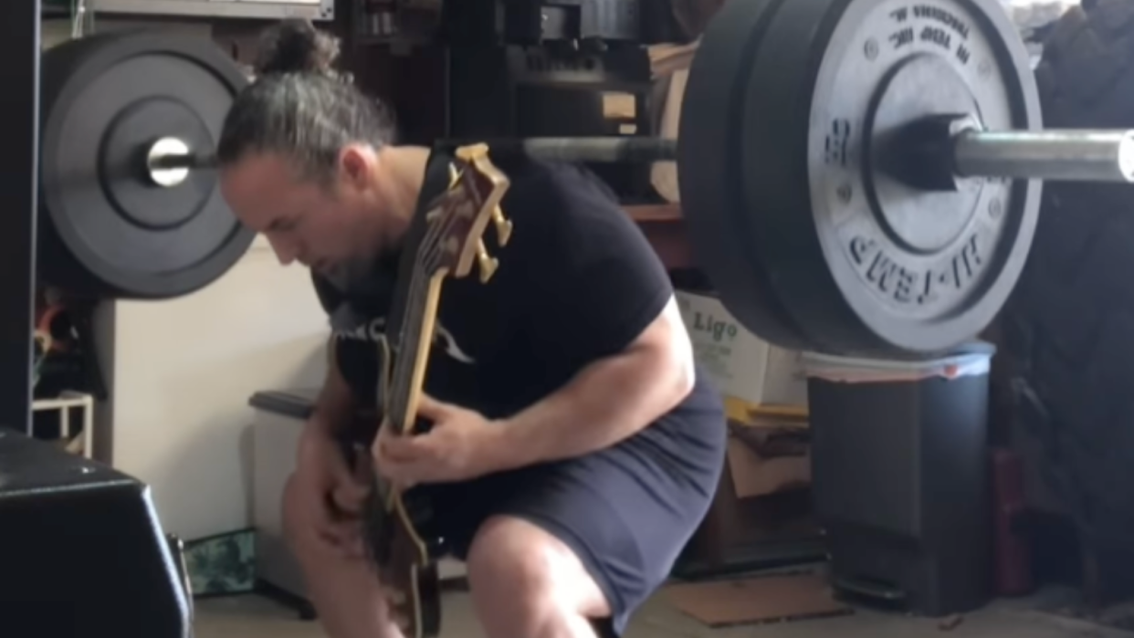  A man squatting 225 pounds while playing a Metallica song. 