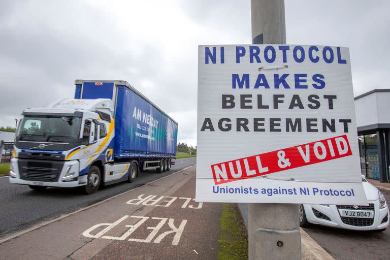 En esta foto de archivo tomada el 17 de mayo de 2022 Un camión pasa junto a una señal contra el "Protocolo de Irlanda del Norte (NI)" mientras se aleja del puerto de Larne, al norte de Belfast, en Irlanda del Norte, tras llegar en un ferry.