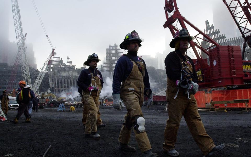 One month after the terrorist attacks on the World Trade Center, firefighters walk past the wreckage to a memorial service 11 October, 2001, in New York - AFP