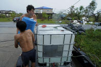 In the aftermath of Hurricane Ida, Terren Dardar, 17, and Dayton Verdin, 14, left, family of Patti Dardar, who works at the marina, pour barrels of rainwater they collected from Tropical Storm Nicholas in Pointe-Aux-Chenes, La., Tuesday, Sept. 14, 2021. They have had no running water since the hurricane, and collected 140 gallons of rainwater in two hours from the tropical storm, which they filter and pump into their house for showers. (AP Photo/Gerald Herbert)